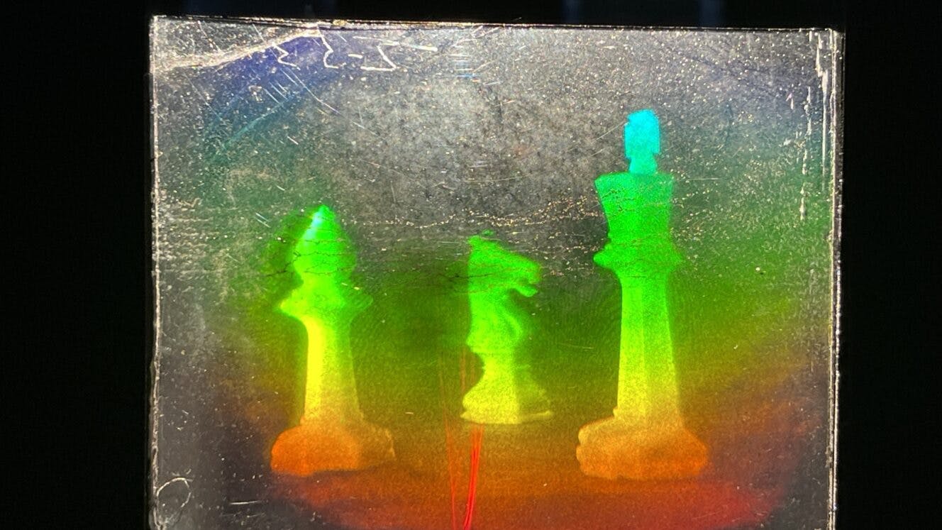 Three chess pieces as a rainbow hologram.