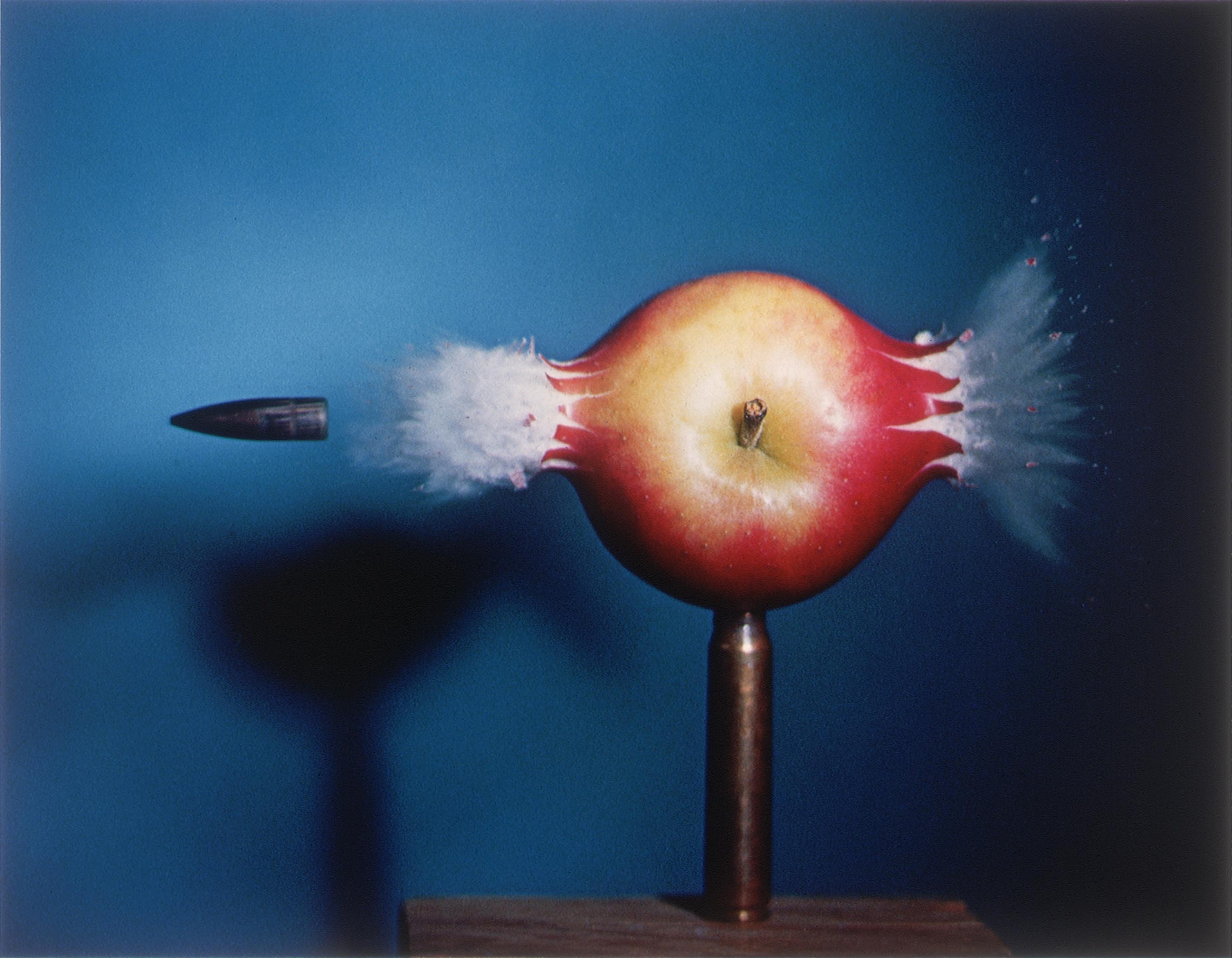 Bullet striking through a red apple.