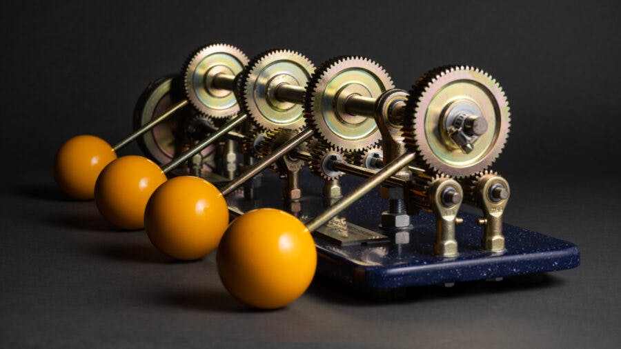 Mechanical device with row of gears, each connected to four yellow orbs.